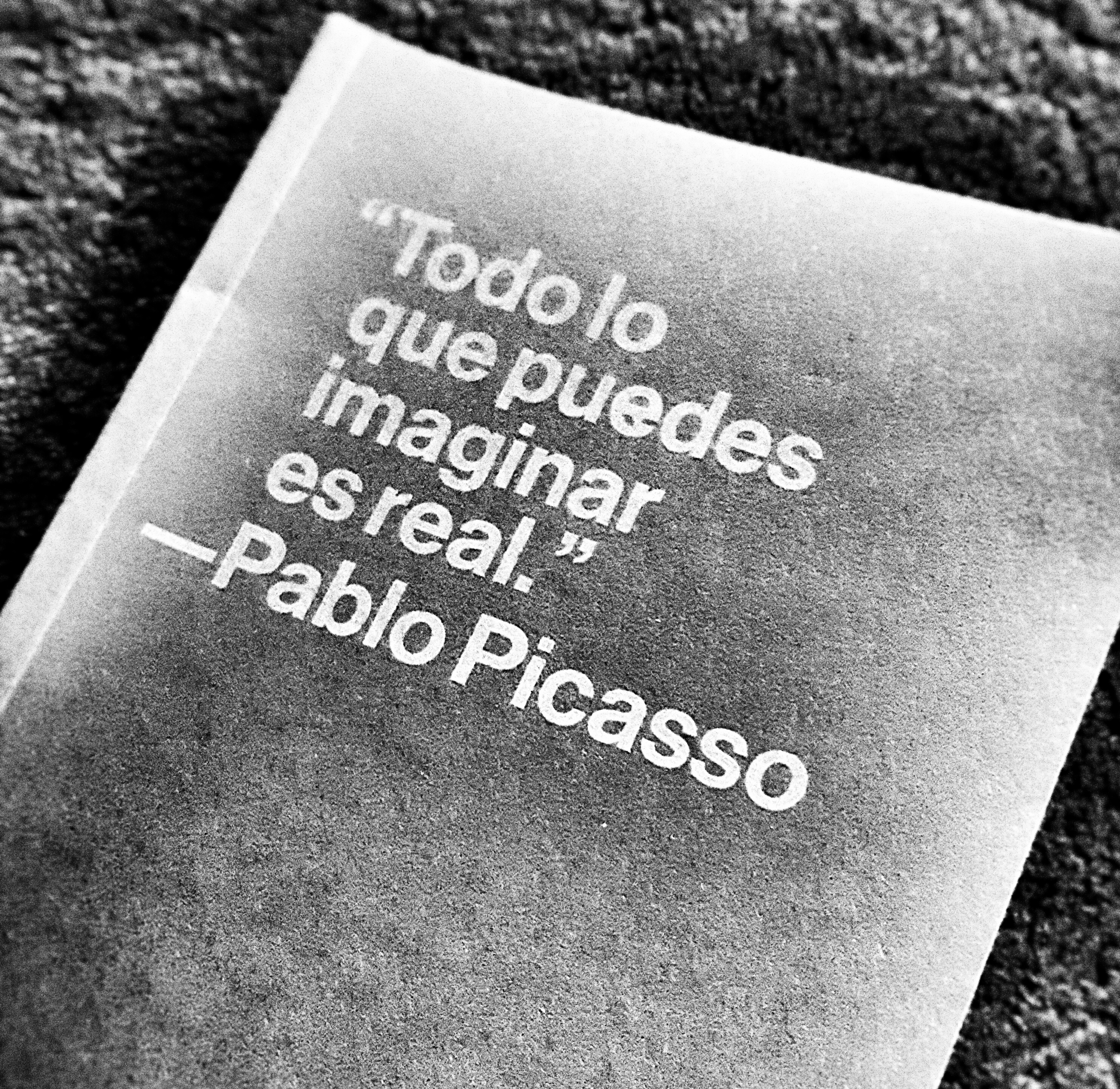 notebook with quote from Picasso in Spanish that translates as "All that you can imagine is real"